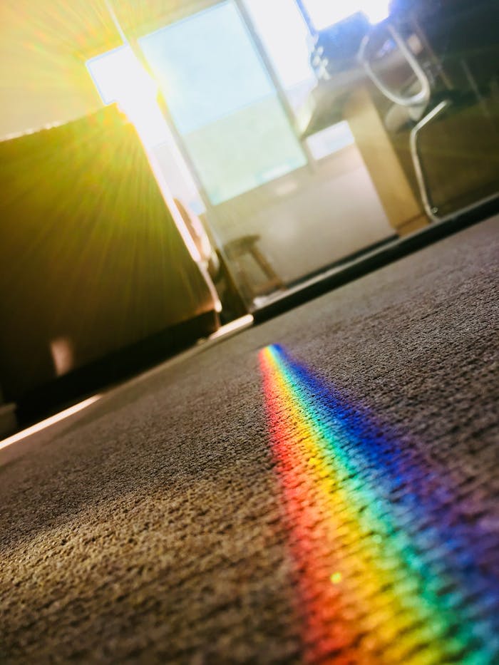 hero-01 A vibrant rainbow reflection on a carpet, created by sunlight passing through crystal glass, adds color to a modern room.